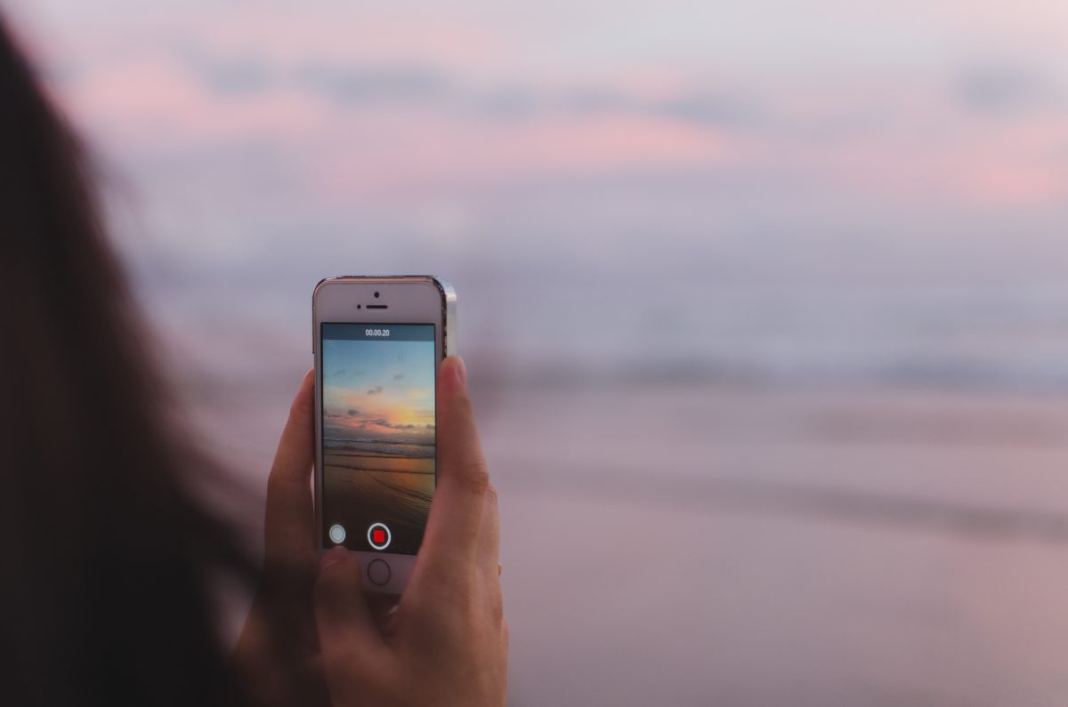 person filming beach on phone for Instagram content